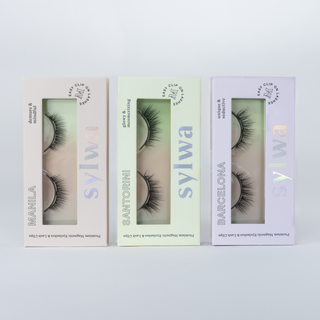 Drei Verpackungen von Sylwa Cosmetics mit magnetischen Wimpern in den Styles 'Manila,' 'Santorini,' und 'Barcelona.' Die eleganten Verpackungen zeigen die natürlichen, hochwertigen magnetischen Wimpern im Dreier Set